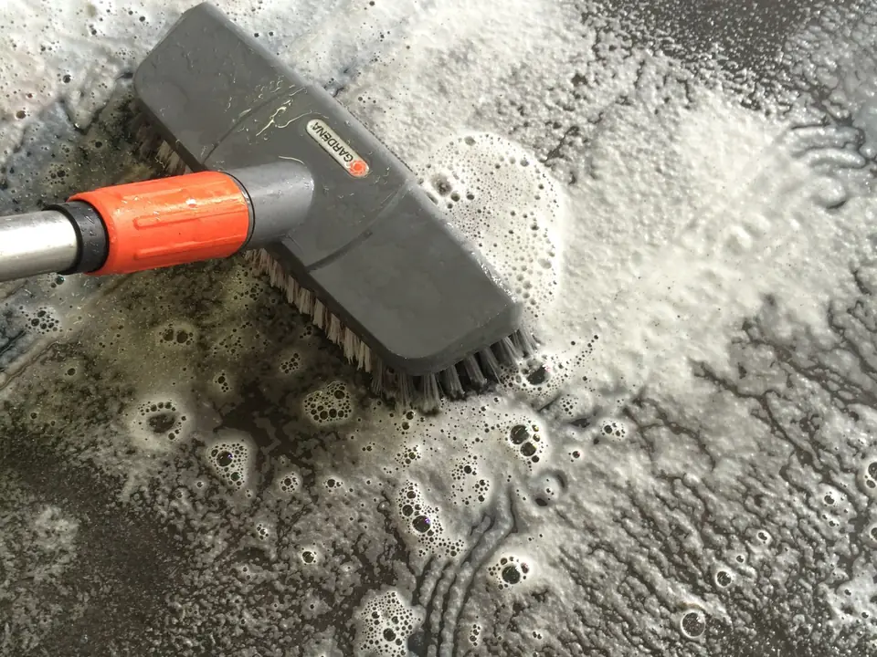 Grauer Schaum mit Schmutz auf einem hellen Teppich während der Wäsche